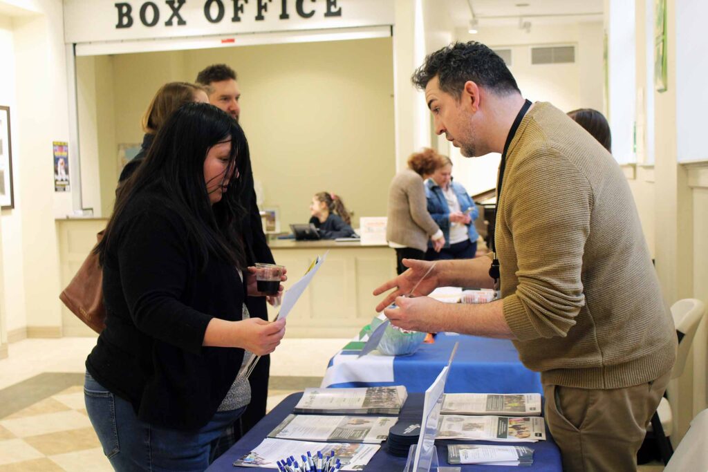 Woman visits with a man at an information table