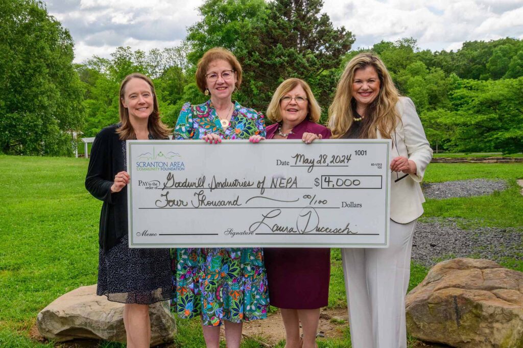 A group of indivdiuals gather around a large presentation check