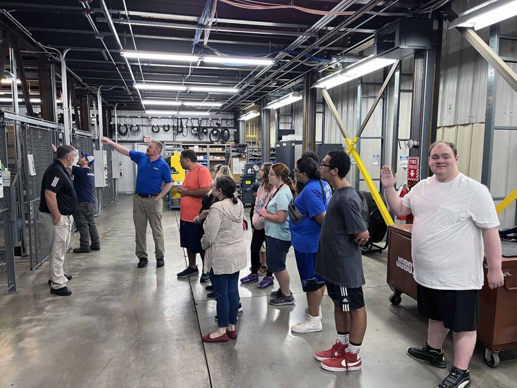A group of high school students receive a tour of a manufacturing facility.
