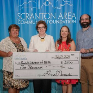 A group of individuals gather around a presentation check.